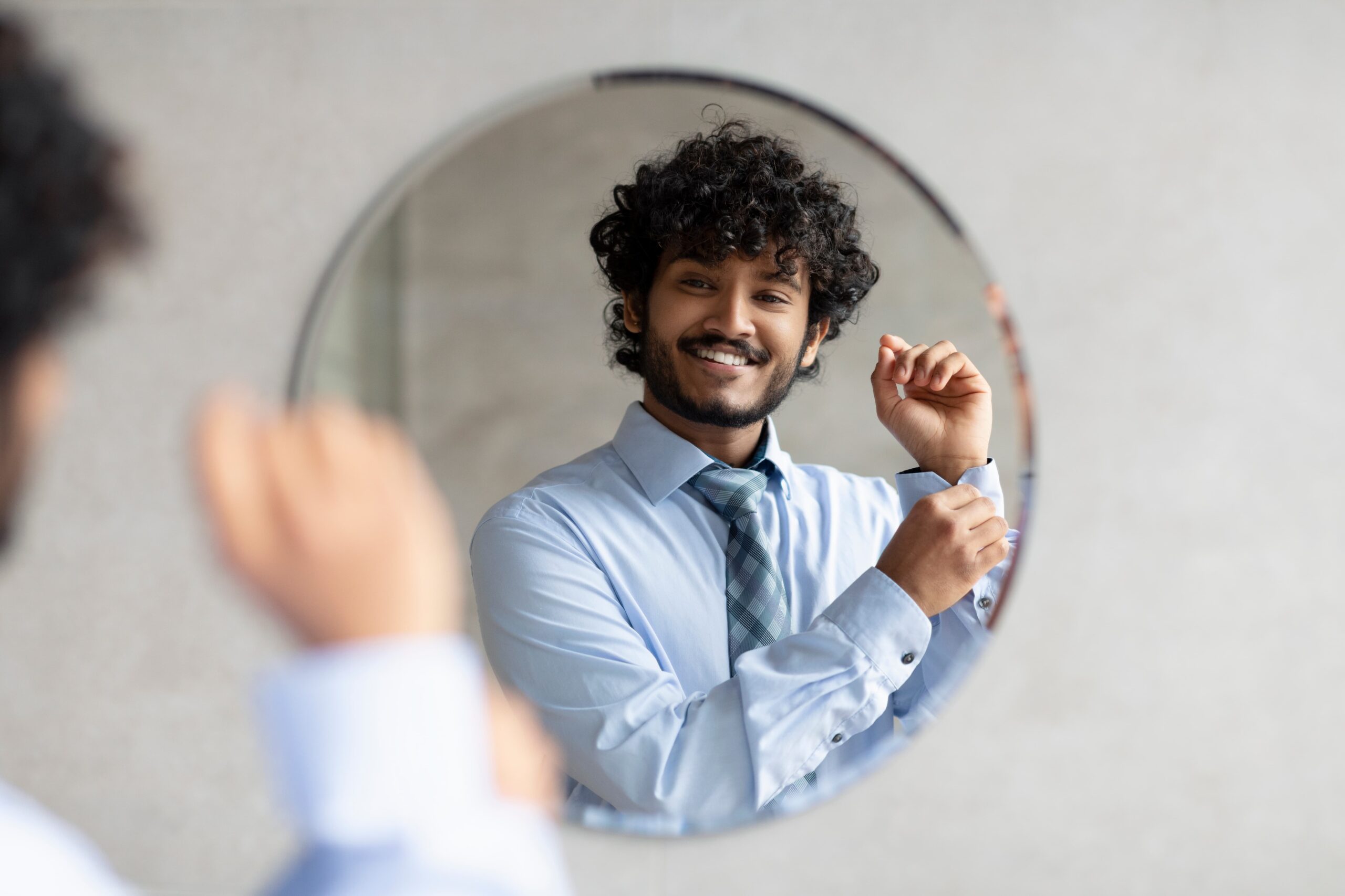 A picture of a happy man adjusting his cufflinks in the mirror
