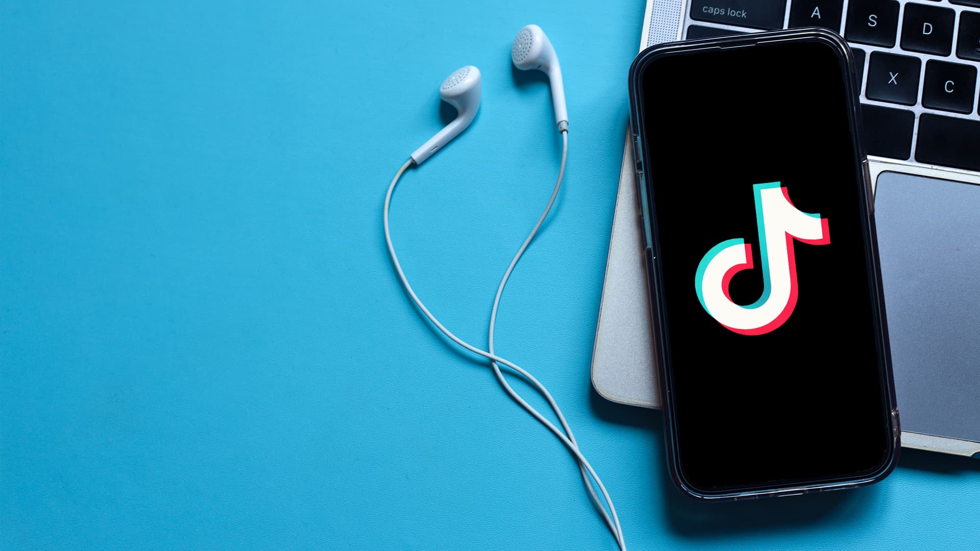 TikTok Marketing. A phone with a TikTok logo on the screen, headphones and a laptop.