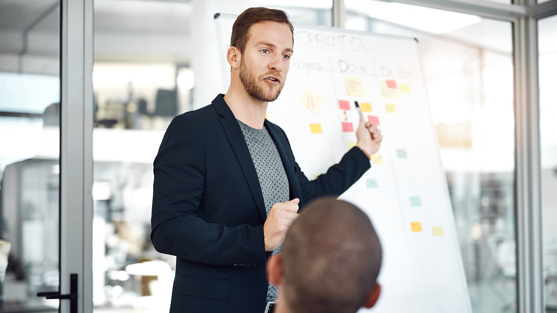 Train the trainer. A man explaining something to his trainees and pointing at the board.
